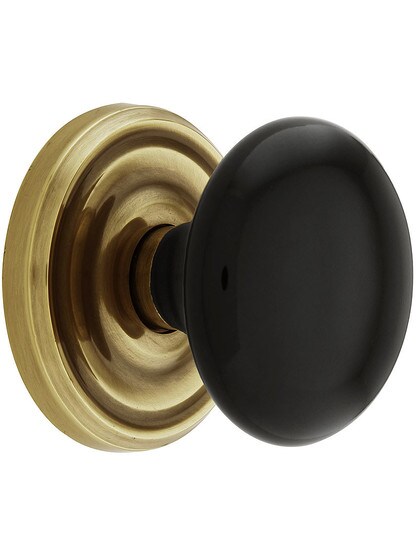 Classic Rosette Set With Black Porcelain Door Knobs in Antique Brass.